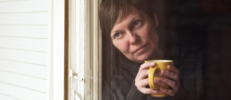 mujer triste tomando café junto a la ventana