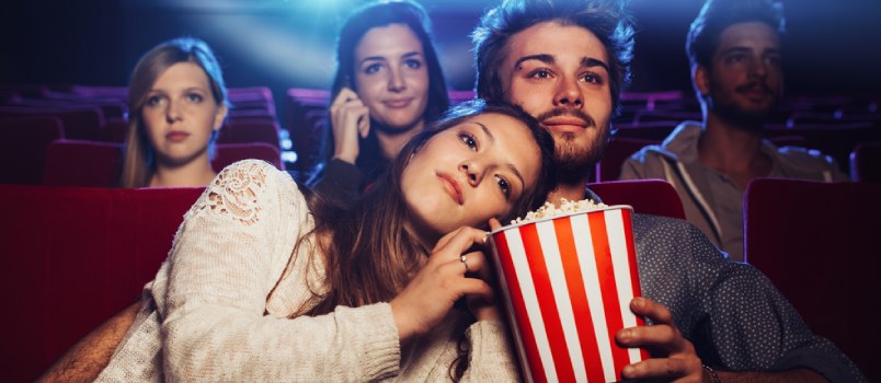 Joven novio y novia viendo una película en el teatro