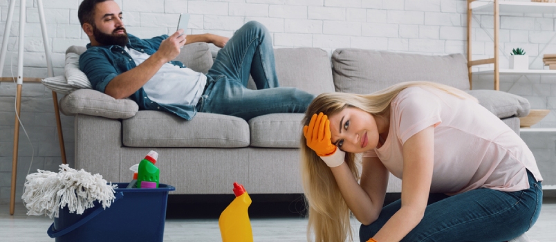 El hombre se acuesta en el sofá y escribe en el teléfono, una mujer triste se aferra a su cabeza y lava los pisos de su casa